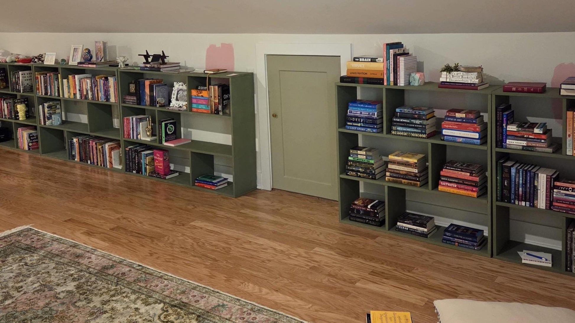 Long row of bookshelves filled with books in a room with wooden flooring.